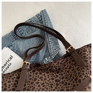 Detail of leopard print tote bag featuring adjustable brown leather strap and gold buckle
