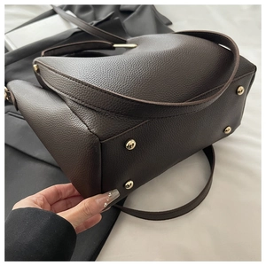 Detail of dark brown pebble leather bag base with golden protective metal studs
