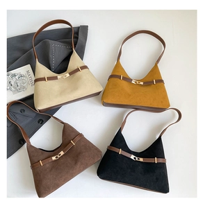 Flat lay of vintage suede tote bags in beige, yellow, brown, and black with gold buckles