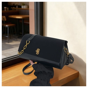 Close-up of black crossbody bag featuring suede texture and gold chain strap detail