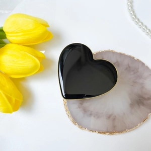 Foldable black heart phone socket with golden edge on marble coaster with flowers
