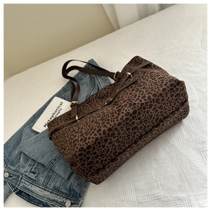 Close-up of leopard print tote bag with brown leather handles and gold metal accents