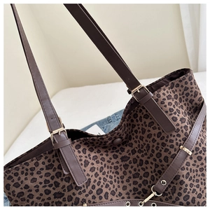 Macro shot of leopard print tote bag detailing textured fabric and dark brown strap buckles