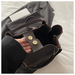 Detail of dark brown lychee leather bucket bag with vintage metallic magnetic closure