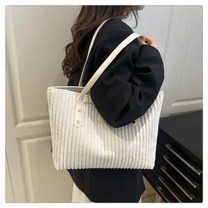 Detailed texture of white corduroy tote bag with thin leather strap on model