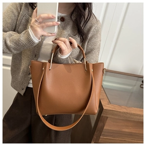 Detail einer braunen Eimer-Tasche aus Leder mit einzigartigem gebogenem Metallgriff