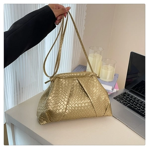 Detail of a woven gold shell bag showing the metallic texture and cloud-like folded shape