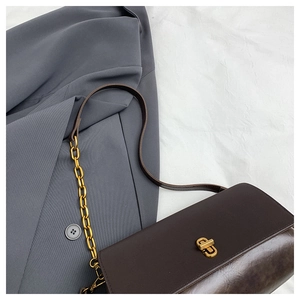 Detail of vintage brown leather handbag with gold twist lock on grey blazer background