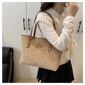 Détail du cabas en velours côtelé beige avec poignées en cuir marron et logo