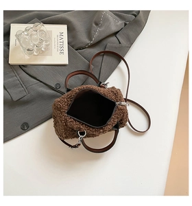 Détail d'un sac à main marron en peluche pelucheuse avec poignée noire sur fond blanc