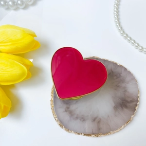 Foldable heart-shaped phone socket in red finish with gold trim on marble tray
