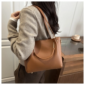 Detailansicht der braunen Bucket Bag aus Leder mit Lychee-Maserung und goldenen Metallteilen