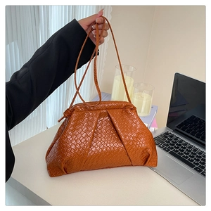 Detailed close-up of brown woven texture and soft pleated design on a shell-shaped bag
