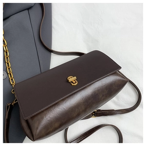 Detail of dark brown leather shoulder bag featuring a minimalist gold rectangular twist lock