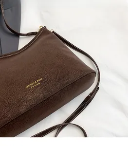 Detail of brown faux leather tote with golden lettering and white contrast stitching