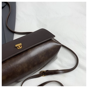 Close-up of chocolate brown faux leather crossbody bag with gold twist lock and smooth texture
