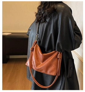 Caramel hobo shoulder bag with knot details shown on black coat for a chic look