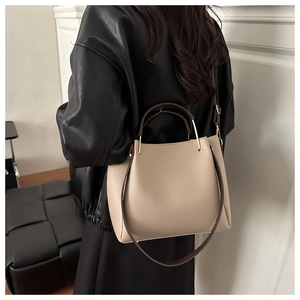 Detail of light beige pebbled leather tote with contrast coffee handles and gold hardware