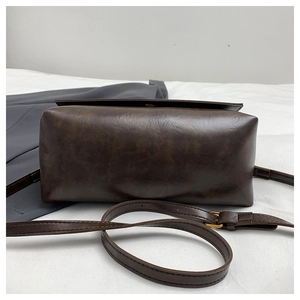 Detailed close-up of dark brown matte leather bag texture with golden adjustable buckle