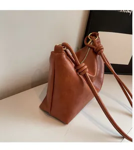 Detailed view of caramel leather shoulder bag featuring knotted strap and golden hardware