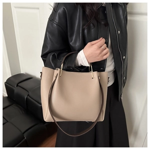 Dettaglio borsa beige testurizzata litchi con tracolla marrone e fibbie metalliche dorate