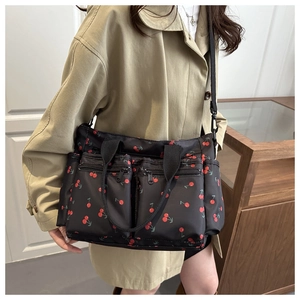 Detail of black nylon tote bag with red cherry print and functional zip pockets