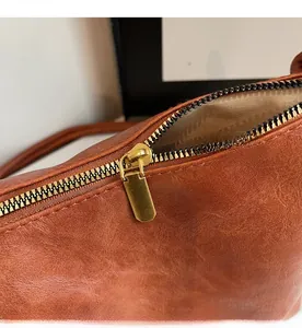Detail of smooth gold zipper and vintage brown faux leather texture on tote bag
