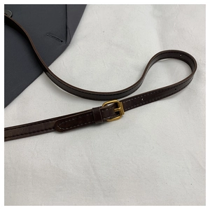 Detail of dark brown leather strap with adjustable gold buckle and fine stitching