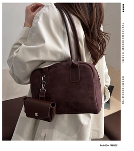 Detail of a vintage dark brown suede baguette bag worn with a white trench coat