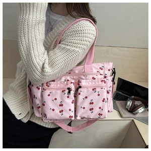 Pink tote bag with cherry print shown in a lifestyle casual setting with a laptop
