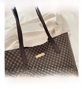 Detail shot of vintage brown monogram tote bag with golden metal logo and flat handles