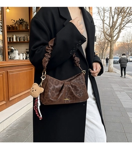 Close-up of brown leopard print shoulder bag with ruched handle and plush bear charm