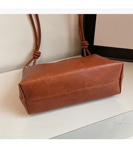 Detail of vintage brown leather crossbody bag with knot texture and soft finish