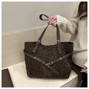 Close-up of leopard print tote bag with brown leather straps and metal buckle detail