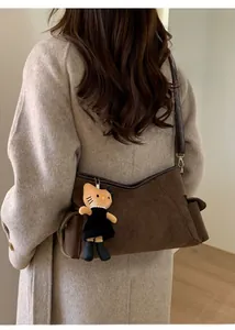 Detail of dark brown suede shoulder bag with a cute Hello Kitty plush charm pendant
