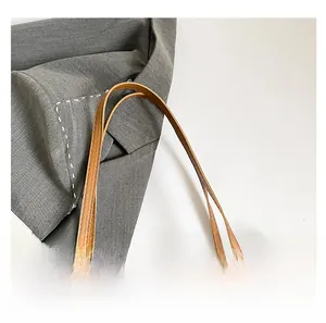 Close-up of brown tote bag with clover pattern and smooth leather handle finish