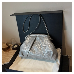 Detailed view of silver woven shell bag with thin strap in elegant black gift box packaging