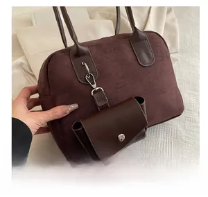 Detail of dark brown suede baguette bag with silver carabiner and mini pouch attachment