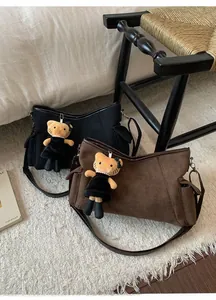 Detail view of matte suede shoulder bags in black and brown with plush cat charms