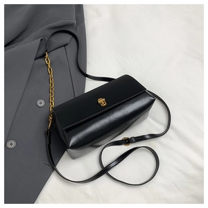 Detail of black leather crossbody bag featuring gold twist lock and chain strap