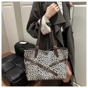 Detail of leopard print tote bag featuring brown leather straps and gold metal hardware