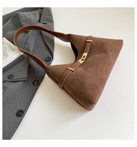 Detail of brown suede tote bag with golden metal buckle and leather strap decoration