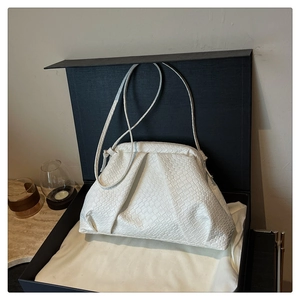 Detailed view of white woven dumpling bag with strap, gift box and dust bag
