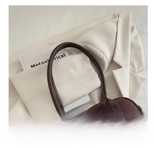 Close-up of comfortable dark brown cylindrical handles on a suede bowling tote bag