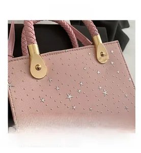 Detail of pink handbag with silver stars, rivet accents and woven handle with gold hardware
