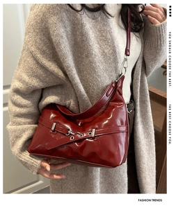 Detailed view of deep red patent leather shoulder bag with vintage metal buckle accent