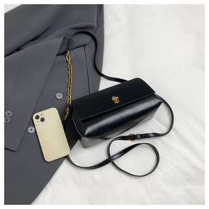 Detailed close-up of a black retro shoulder bag featuring a golden buckle and chain strap