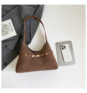 Close-up of brown suede tote bag featuring leather strap, metal hook, and minimalist style
