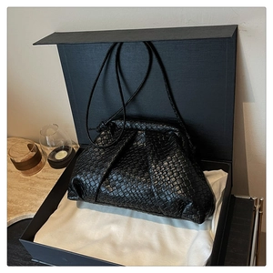 Detailed view of black woven texture shell bag on ivory cloth in elegant setting
