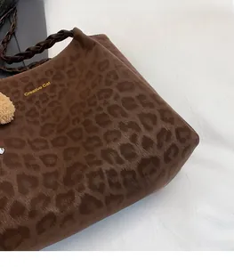 Dettaglio della borsa leopardata con manico intrecciato e ciondolo di peluche